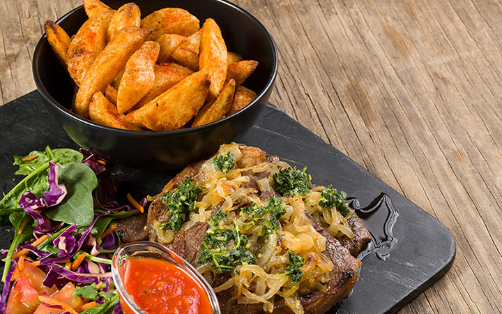 Pan-fried steaks with caramalised onions, pesto and served with spicy wedges and home-made tomato sauce