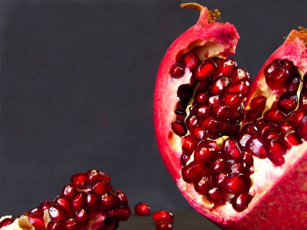 Split open pomegranate to revel ruby red arils
