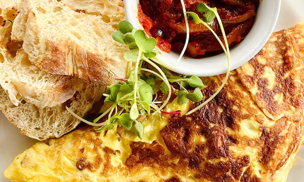 A perfectly cooked omelet with two slices of baked bread and a tomato relish by Stretta Cafe - Hillcrest Restaurants 