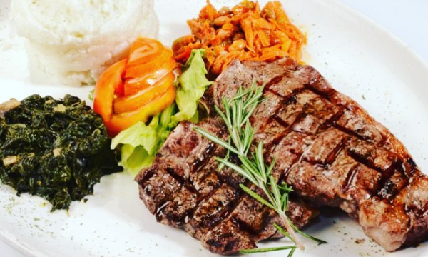A Sunday lunch consisting of chargrilled steaks, pap, spinach and vegetables by Restaurant Vilakazi - Vilakazi Street Restaurants