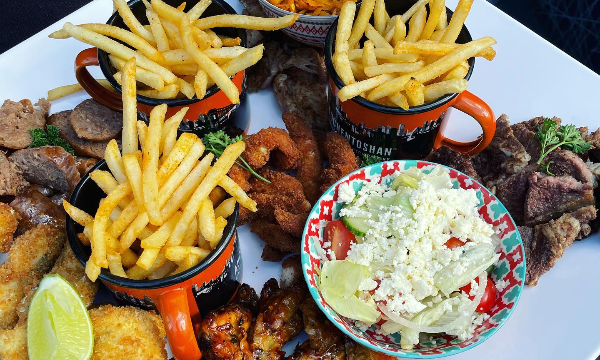 A fan favourite Society 88 platter for four consisting of french fries, a Greek salad, chicken pops, chicken wings, sausage and steak by Society 88 -Vilakazi Street Restaurants