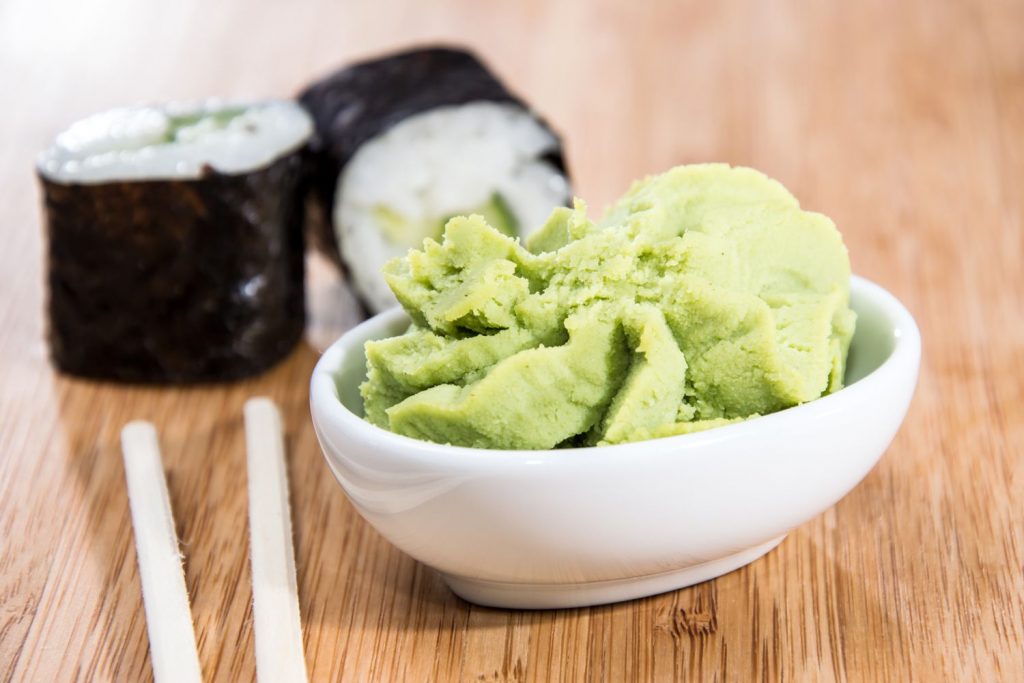 Wasabi in a bowl next to two sushi rolls